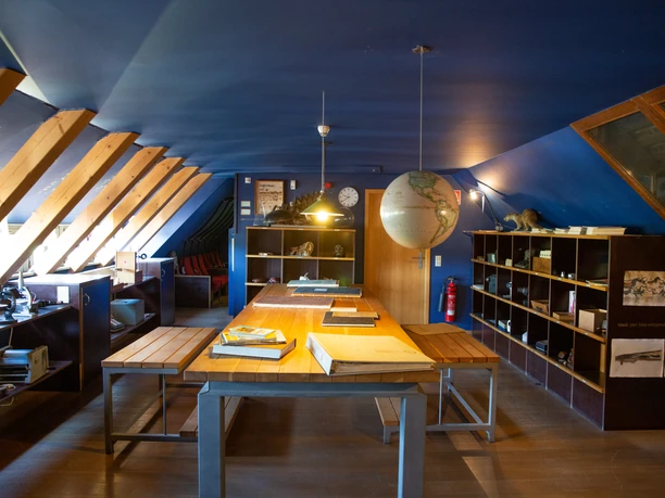 Themenwelt Idee Holzvertäfelte Dachstube mit Schreibtischen und Regalen, beleuchtet von Hängelampen.