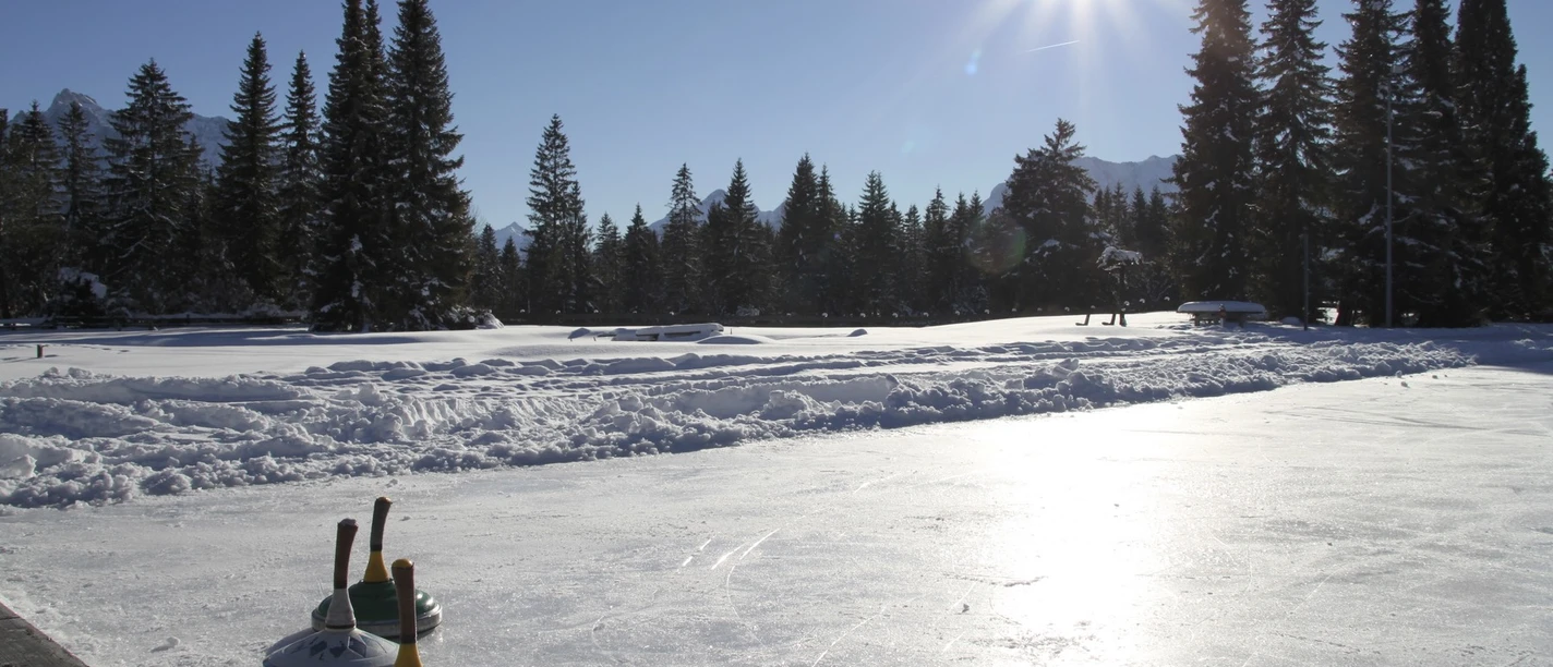 Natur-Eisplatz in Wallgau im Winter mit Sonnenschein
