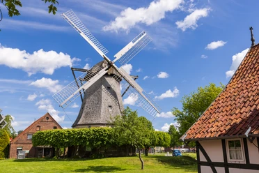 Windmühle Destel Eine historische Windmühle mit großen Flügeln, umgeben von traditionellen Gebäuden und Bäumen.
