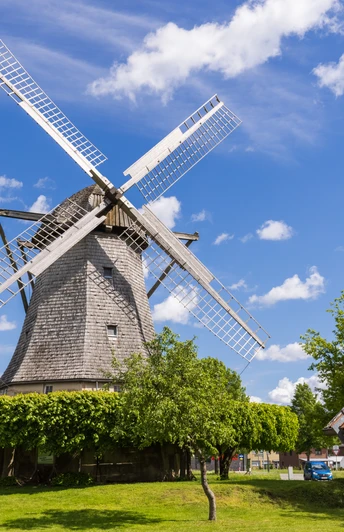 Windmühle Destel Eine historische Windmühle mit großen Flügeln, umgeben von traditionellen Gebäuden und Bäumen.
