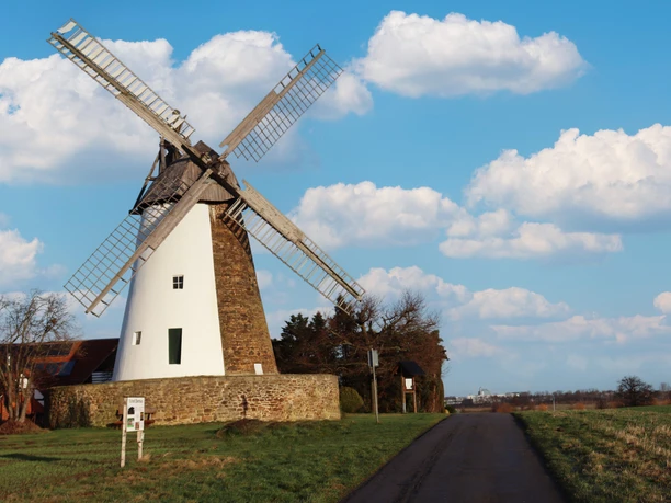 Windmühle Eickhorst in ländlicher Umgebung, blauer Himmel mit weißen Wolken, gepflasterter Weg.