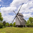Bockwindmühle Oppenwehe Die historische Bockwindmühle Oppenwehe steht an grüner Wiese, umgeben von Bäumen und blauem Himmel.