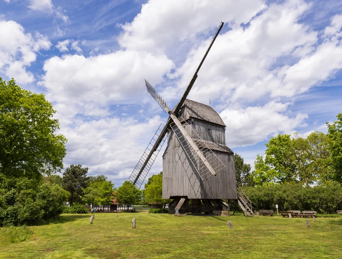 Bockwindmühle Oppenwehe Die historische Bockwindmühle Oppenwehe steht an grüner Wiese, umgeben von Bäumen und blauem Himmel.