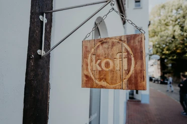 Minden - kofi-79.jpg Das Bild zeigt ein Holzbrett mit dem Geschäftsnamen.