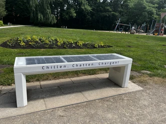 SmartBench SmartBench mit integriertem Solarpanel in einem grünen Park, ausgestattet mit dabei USB-Ladeanschlüssen.