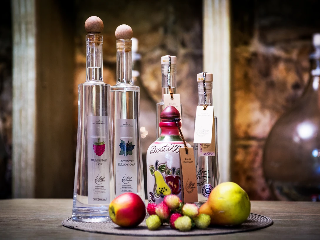 Pirna stokerij Verschiedene Flaschen mit Spirituosen auf einem Tisch, umgeben von frischem Obst wie Äpfeln und Birnen, vor einem rustikalen Hintergrund.Various bottles of spirits on a table, surrounded by fresh fruit such as apples and pears, against a rustic backdrop.Různé láhve lihovin na stole, obklopené čerstvým ovocem, jako jsou jablka a hrušky, na rustikálním pozadí.Różne butelki alkoholi na stole, otoczone świeżymi owocami, takimi jak jabłka i gruszki, na rustykalnym tle.Verschillende flessen sterke drank op een tafel, omringd door vers fruit zoals appels en peren, tegen een rustieke achtergrond.Varie bottiglie di liquori su un tavolo, circondate da frutta fresca come mele e pere, su uno sfondo rustico.