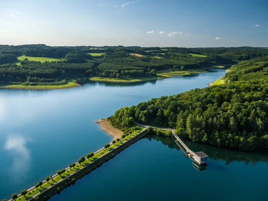 Dhünn- Talsperre Stausee mit umliegenden dichten Wäldern unter blauem Himmel, Blick aus der Vogelperspektive.