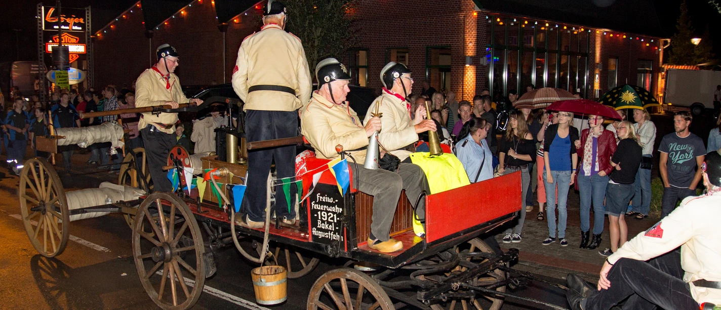 FDL1000_02.jpg Feuerwehrparade mit historischem Löschwagen und verkleideten Teilnehmern bei Nacht in Augustfehn.