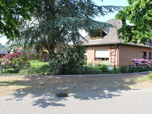 A red brick house with a well-tended garden and flowering shrubs; a welcoming place.