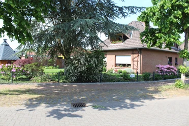 Fam. Jäger Ein rotes Backsteinhaus mit gepflegtem Garten und blühenden Sträuchern; ein einladender Ort.