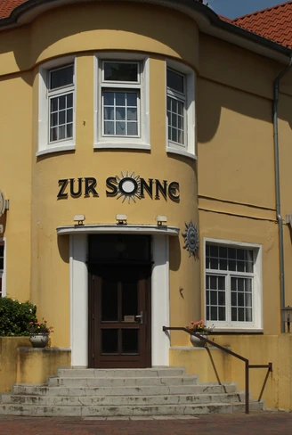Gelbes Gebäude des Hotel zur Sonne mit roten Dächern und seitlichen Treppen.Yellow building of the Hotel zur Sonne with red roofs and side stairs.Hotel zur Sonnes gule bygning med røde tage og sidetrapper.Geel gebouw van Hotel zur Sonne met rode daken en zijtrappen.