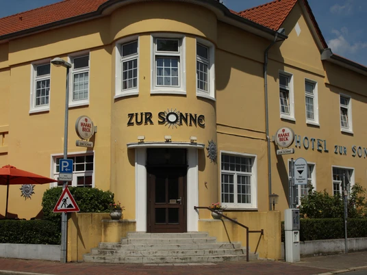 Gelbes Gebäude des Hotel zur Sonne mit roten Dächern und seitlichen Treppen.Yellow building of the Hotel zur Sonne with red roofs and side stairs.Hotel zur Sonnes gule bygning med røde tage og sidetrapper.Geel gebouw van Hotel zur Sonne met rode daken en zijtrappen.