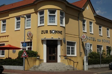 Hotel zur Sonne Gelbes Gebäude des Hotel zur Sonne mit roten Dächern und seitlichen Treppen.