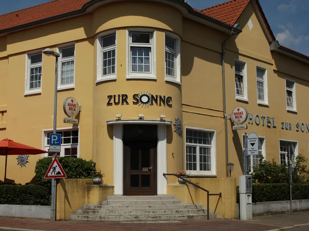 Hotel zur Sonne Gelbes Gebäude des Hotel zur Sonne mit roten Dächern und seitlichen Treppen.