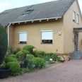 Ein schlichtes Einfamilienhaus aus gelbem Klinker mit Dachfenster, Vorplatz und gepflegtem Vorgarten.