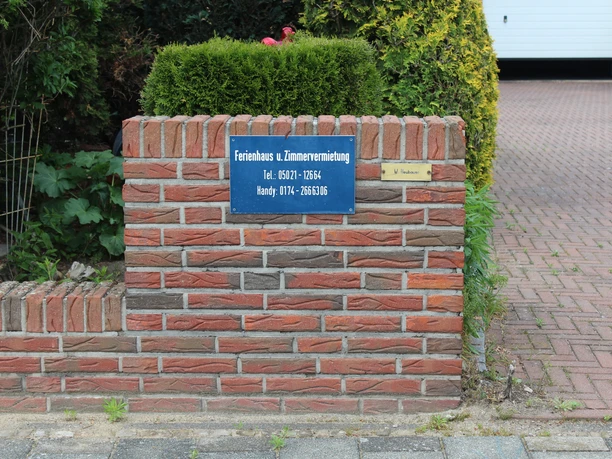 Information about the vacation home and room rental, with a telephone number on a brick sign.