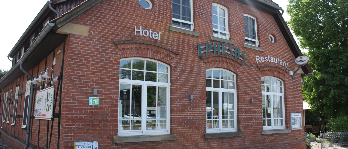 Gebouw van rode baksteen met grote ramen. Opschrift "Ephesus" en verwijzing naar het hotel en restaurant.