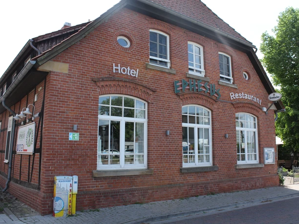 Red brick building with large windows. Inscription "Ephesus" and reference to hotel and restaurant.