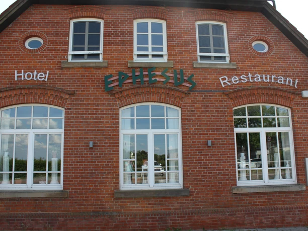 Historisch bakstenen gebouw met grote witte ramen, "Efeze"-belettering, aan de stuw van de Weser.