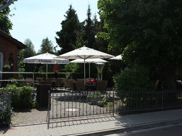Hotel en restaurant Ephesus aan de stuw van de Weser met een zonnig terras omgeven door groene bomen.