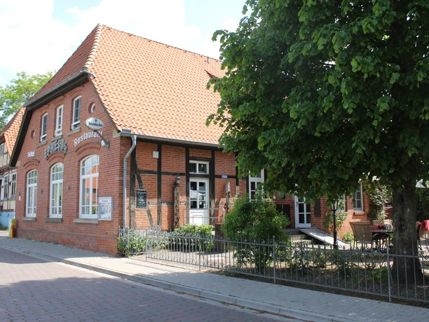 Hotel und Restaurant Ephesus am Weserwehr Restaurant Ephesus am Weserwehr, ein Backsteinhaus mit roten Dachziegeln, umgeben von Grün.