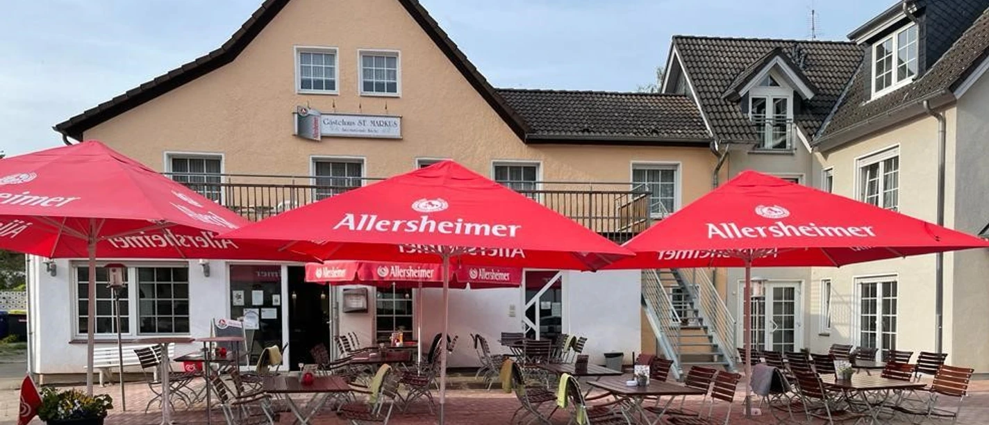 st-markus-restaurent-geastezimmer.jpg Terrasse des Gästehauses mit Tischen und Sonnenschirmen