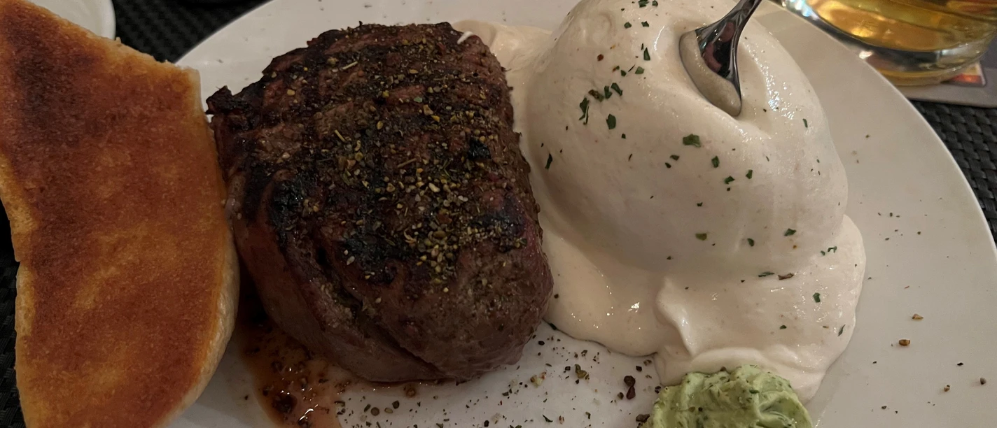 A juicy fillet steak, accompanied by a generous portion of herb butter and bread as well as mushroom puree.