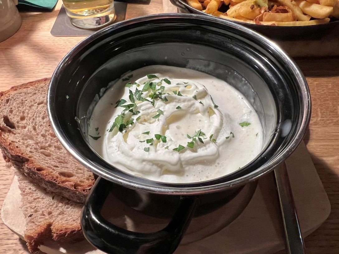 Cremige Spargelsuppe in einem schwarzen Topf, garniert mit Petersilie, serviert mit Brot.Creamy asparagus soup in a black pot, garnished with parsley, served with bread.Cremet aspargessuppe i en sort gryde, pyntet med persille, serveret med brød.Romige aspergesoep in een zwarte pot, gegarneerd met peterselie, geserveerd met brood.