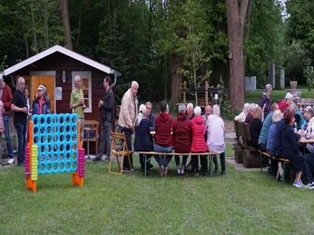Spiel, Spaß und Geselligkeit auf dem Mehrgenerationenplatz Menschen verschiedener Generationen unterhalten sich gesellig an Biertischen in der Natur.