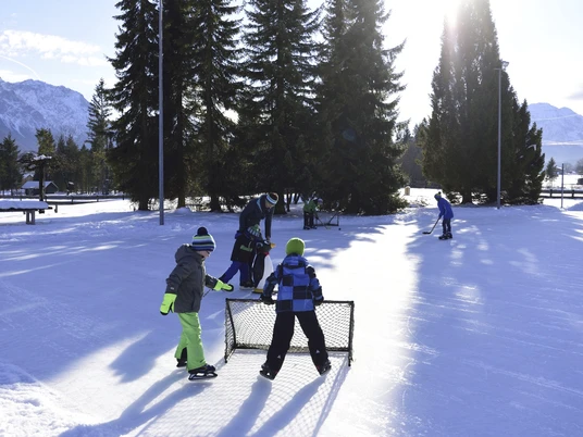 Schlittschuhlaufen und Eishockey spielen auf dem Natur-Eisplatz in Krün Winter