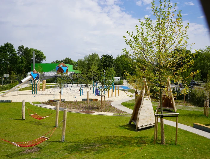 Überblick Spielgelände Moderner Spielplatz mit Klettergerüsten, Rutschen und Hängematten, umgeben von grüner Landschaft.