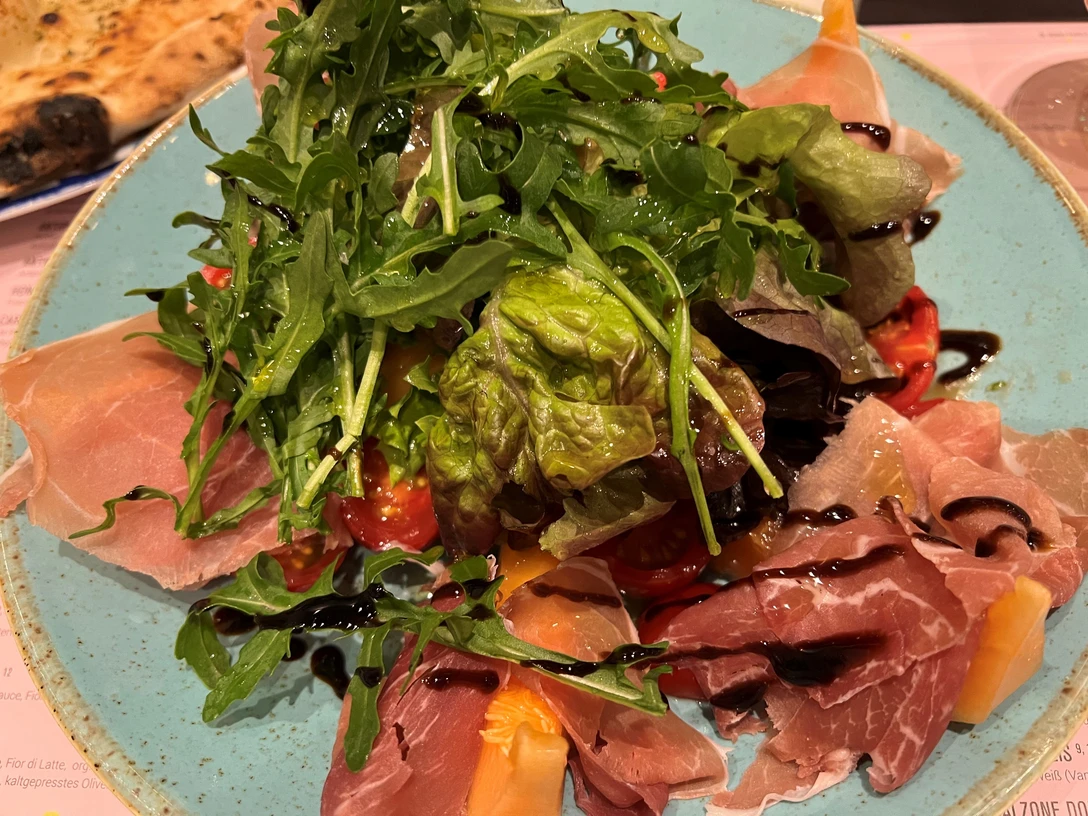 Salat Ein bunter Salatteller mit Rucola, Parmaschinken und buntem Gemüse, dezent mit Balsamico beträufelt.