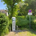 Ladesäule Kölner Straße Ladesäule für Elektrofahrzeuge zwischen grünen Hecken, daneben Parkverbots- und Reserviert-Schild.