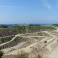 Steinbruch Lindlar Weitläufiger Steinbruch mit terrassierten Abbauflächen und Baumaschinen vor bewaldeter Hügellandschaft.