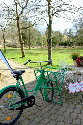 Grünes Fahrrad vor einem rustikalen Backsteinbogen, daneben ein Schild zur Gutshof Brennerei Begatal.