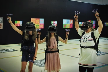 7th Space VR Langenfeld Drei Personen in virtueller Realität mit Headsets und Controllern in einem Indoor-Areal.