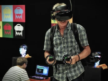 7th Space VR Langenfeld Mann mit VR-Brille und Controllern erlebt virtuelle Realität in einer modernen Ausstellungsumgebung.