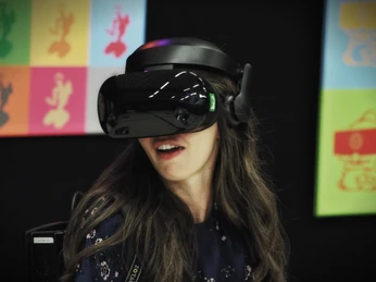 7th Space VR Langenfeld Eine Person trägt eine VR-Brille in einem Raum mit bunten Postern und erlebt virtuelle Realität.