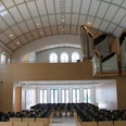 Kreuzkirche Wiedenbrück Moderner Kirchenraum mit geschwungenem Dach, Orgel links, hellem Holz, leeren Stuhlreihen und Fenstern.