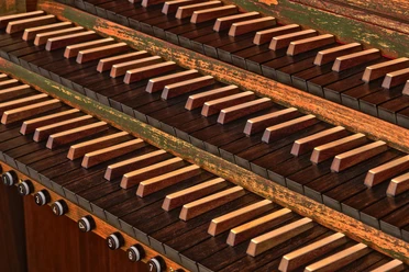Orgel Nahaufnahme von Orgelmanualen mit holzbesetzten Tasten und eleganten Registerzügen darunter.