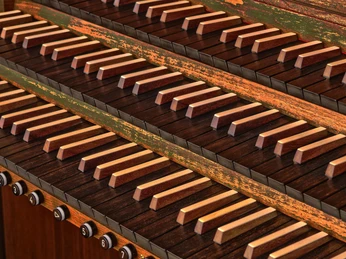 Orgel Nahaufnahme von Orgelmanualen mit holzbesetzten Tasten und eleganten Registerzügen darunter.