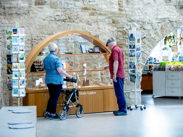 Altenberger Dom-Laden Ein älteres Paar betrachtet Ausstellungsstücke in einem Dom-Laden, er zeigt auf religiöse Artikel.