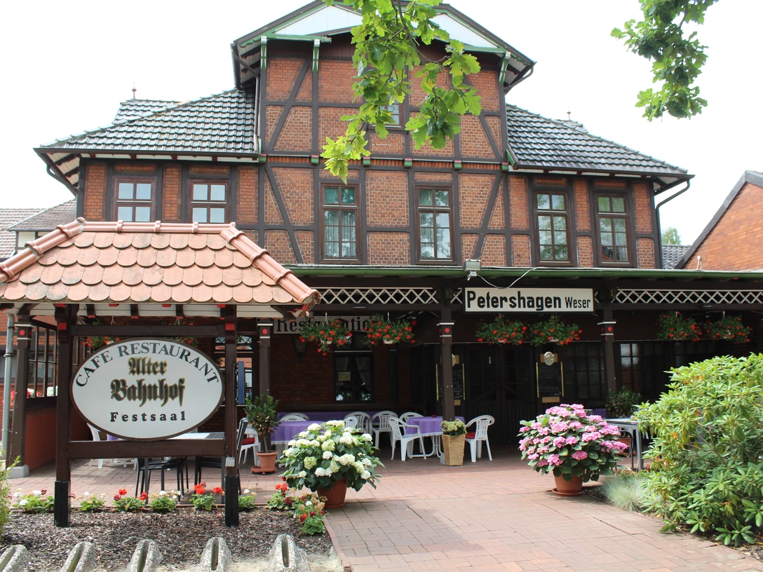 Gasthaus Kupfersaal Backsteinbau mit Fachwerkelementen und dekorierten Tischen im Außenbereich, umgeben von Blumen.
