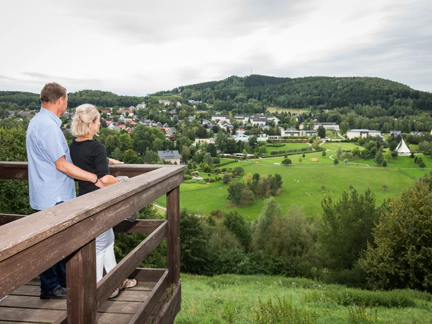 Blick auf Bad Schlema Ein Paar blickt von einem Holzsteg auf die grüne Landschaft und das Dorf Bad Schlema.