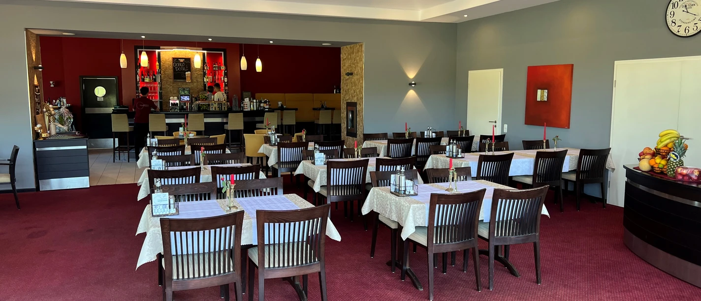 Gastronomie Panorama am Golfplatz Ein Restaurant mit roten Wänden, gedeckten Tischen und einem modernen Ambiente neben einem Golfplatz.
