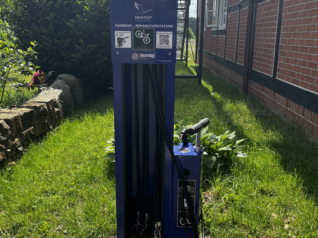 Fahrrad-Reparaturstation Mardorf Fahrrad-Reparaturstation in Mardorf, umgeben von grünem Rasen, neben einem Fachwerkhaus platziert.