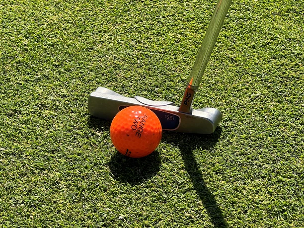 Golfball Ein leuchtend orangefarbener Golfball liegt auf einem gepflegten Rasen, bereit für den nächsten Schlag.