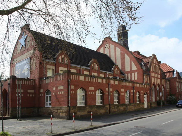 Kultur-Bahnhof Bochum-Langendreer Altes rotes Backsteingebäude mit gemusterten Ziegeln, großen Fenstern und einem hohen Schornstein.