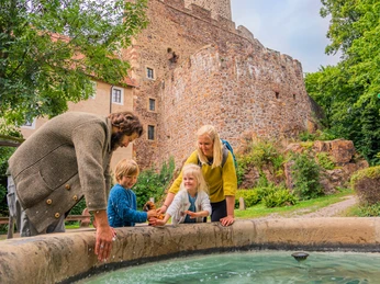 Burg Gnandstein - Sehenswürdigkeiten in der Leipzig Region Blick auf die imposante Burg Gnandstein, im Vordergrund spielt eine Familie am Burgbrunnen mit dem Wasser, Familie, Freizeit, Kinder, Ausflug