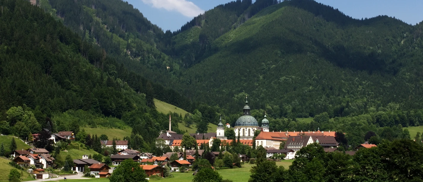 Ettal Blick auf das Kloster Ettal mit umgebenden Wäldern und Bergen an einem sonnigen Tag.